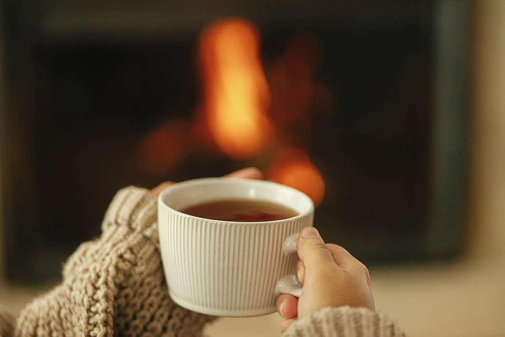 hands-in-cozy-sweater-holding-cup-of-warm-tea